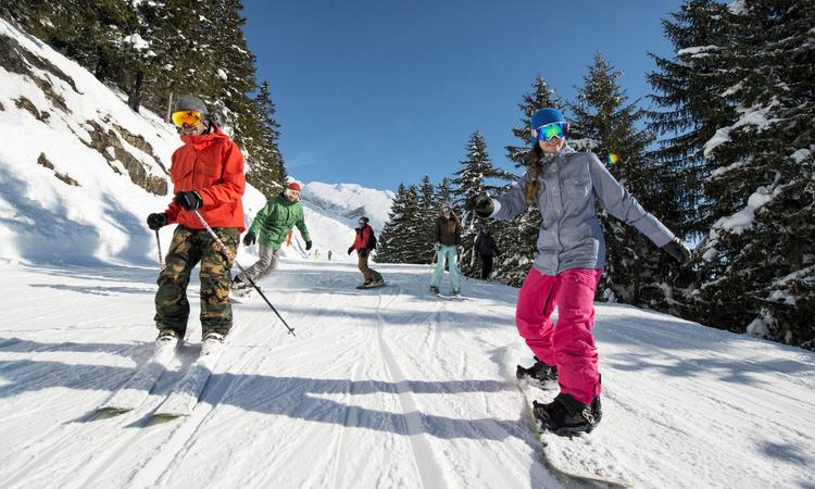 Group of friends skiing down tree lined slope in La Clusaz
