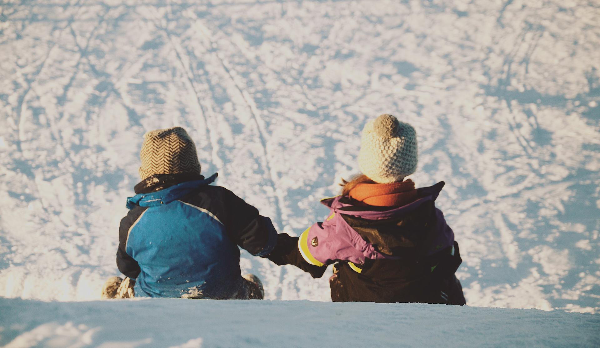 Two children holding hands sitting on a hill
